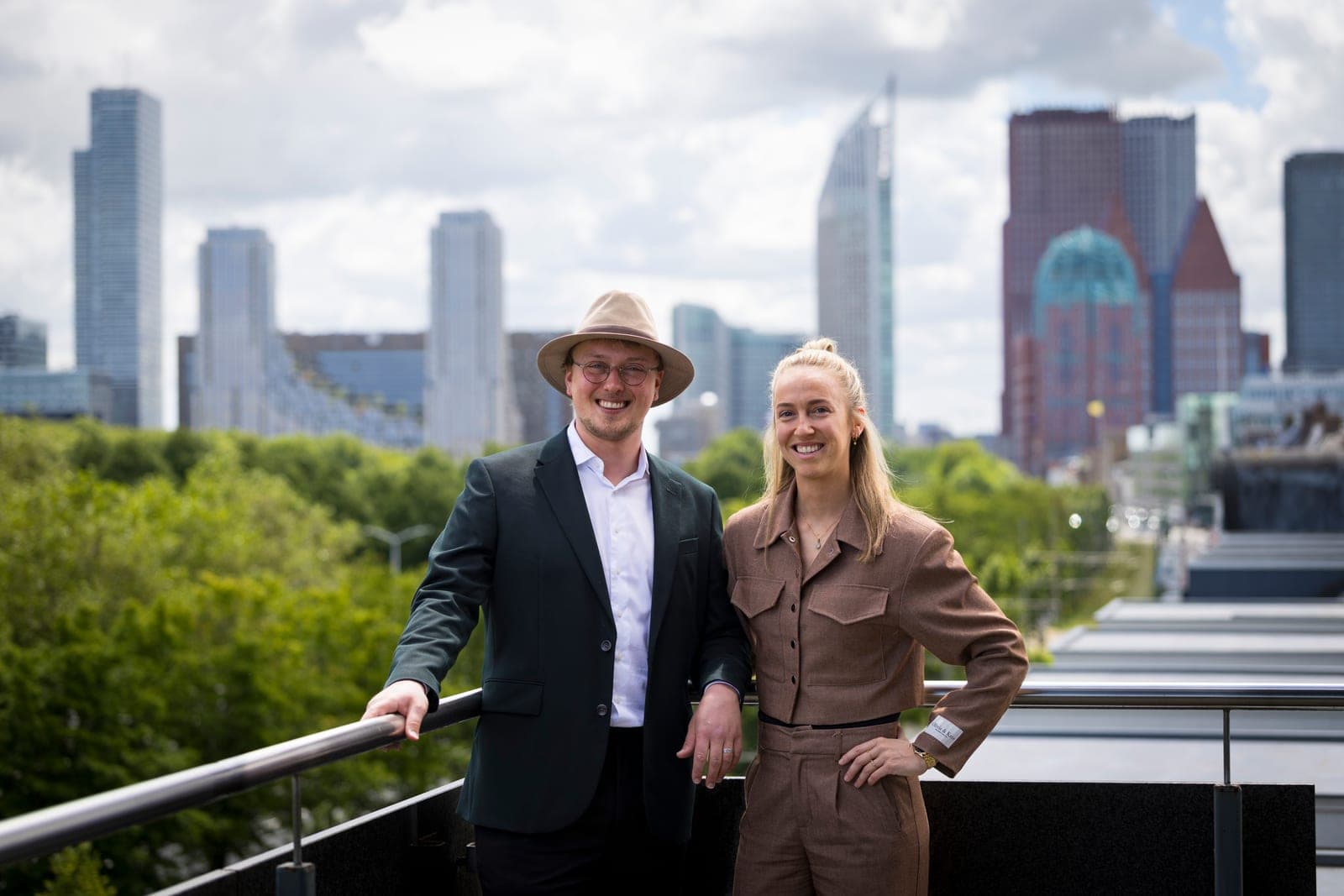 Mandy van Dijk en Ronald Trouwen, oprichters van Statements, op een dakterras met de skyline van Den Haag op de achtergrond
